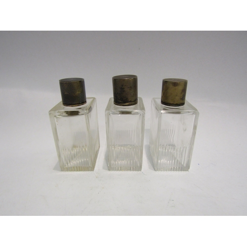 4317 - A set of three silver lidded cut glass bottles, all with engine turned decoration, hallmarked London... 