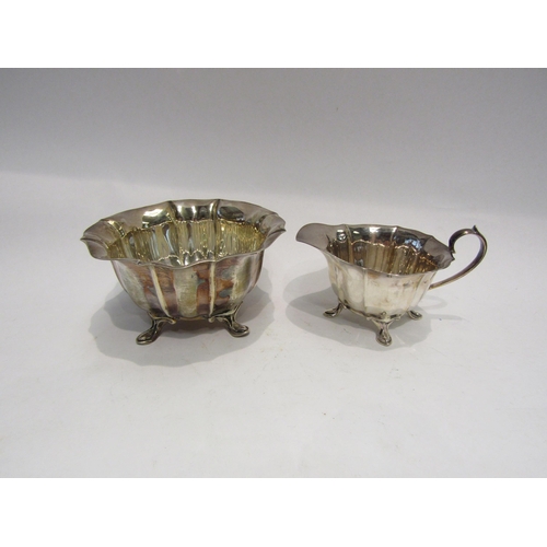 4319 - A silver cream jug and sugar bowl, fluted form with wavy edge rim.  Sugar bowl on pad feet