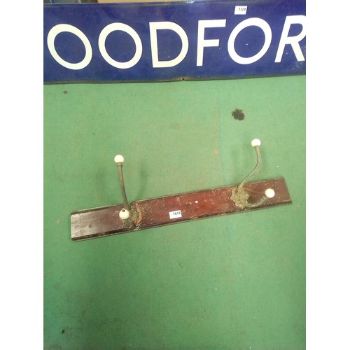 7610 - A pair of brass and ceramic double coat hooks on wooden mount    (R)  £15