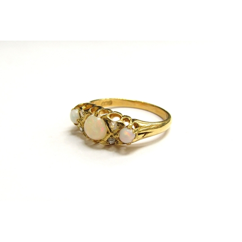 9295 - A gold ring set with three circular opals spaced by two old cut diamonds, stamped 18ct. Size L, 3g