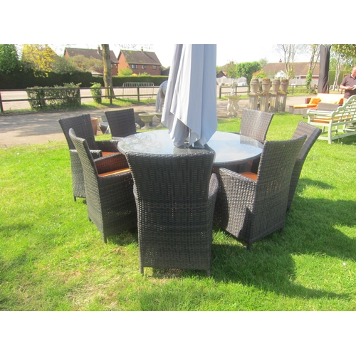 3621 - A circular glass top wicker effect garden table with eight chairs, cushions and a parasol