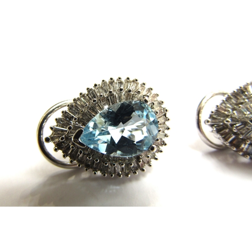 9028 - A pair of diamond and topaz cluster earrings the pear cut blue topaz framed by two rows of baguette ... 