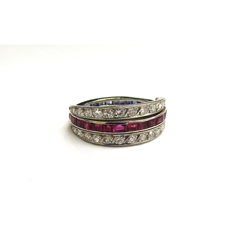 9034 - A white metal night and day ring, with half band of rubies and half band of sapphires with two hinge... 