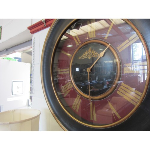 1057 - A black/maroon/gold circular quartz wall clock, roman numerated chapter ring, 63cm diameter