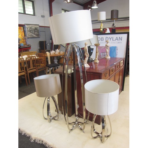 1079 - A chrome effect standard lamp with a pair of matching table lamps, cream shades