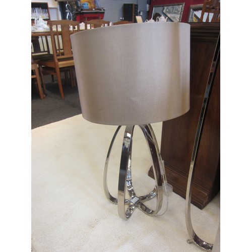 1079 - A chrome effect standard lamp with a pair of matching table lamps, cream shades