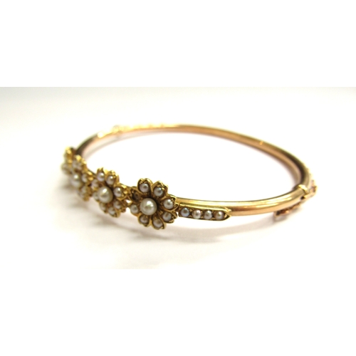 9023 - A Victorian gold hinged bangle with four flowers set with split pearls (three missing) unmarked, 6cm... 