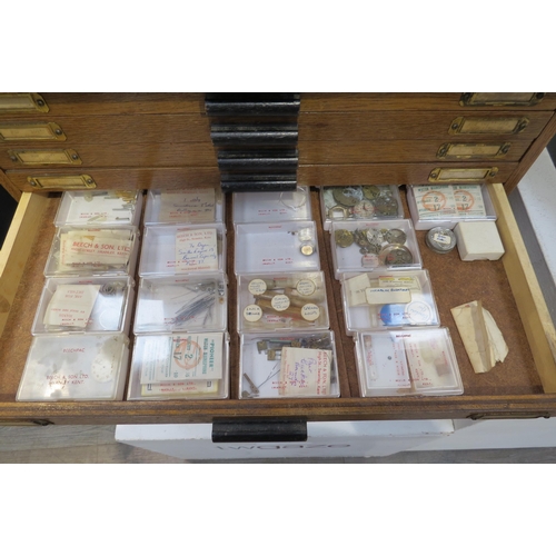 8253 - An oak 20 drawer watch makers cabinet with contents mainly 20th swiss watch parts boxed and labelled... 