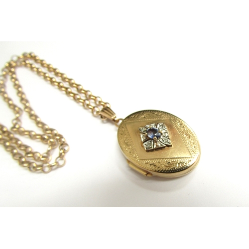 9465 - A 9ct gold oval double photograph locket with engraved decoration and sapphire to centre framed by d... 