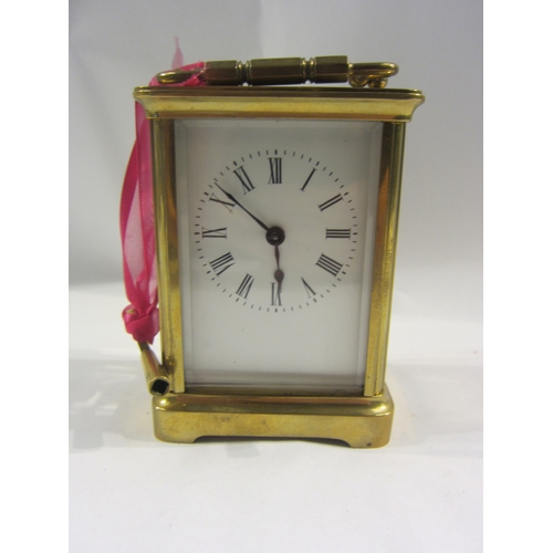 4332 - A brass cased carriage clock with key.  Bevelled glass side and door panels