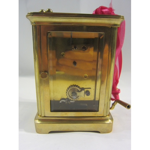 4332 - A brass cased carriage clock with key.  Bevelled glass side and door panels