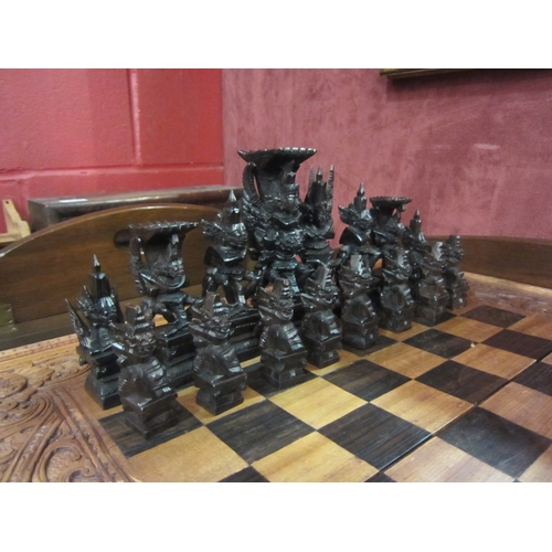 4187 - A Balinese heavily carved chess/backgammon set with tribal style carved bespoke pieces