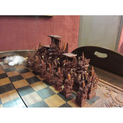 4187 - A Balinese heavily carved chess/backgammon set with tribal style carved bespoke pieces