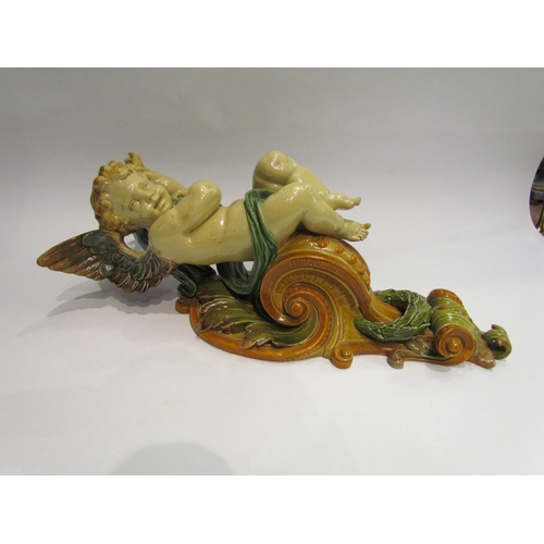 4406 - A majolica wall bracket, putti aloft acanthus leaf and laurel wreath, 39cm tall.  Hairline cracks to... 