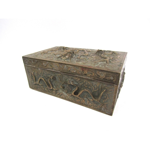 5019 - A cast brass casket with raised decoration bearing dragons, velvet lined interior with six character... 