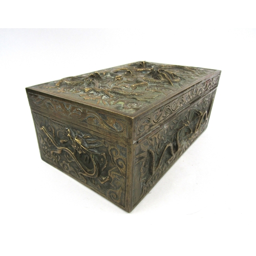 5019 - A cast brass casket with raised decoration bearing dragons, velvet lined interior with six character... 