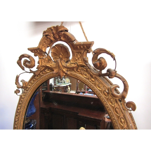 5472 - A 19th Century gilt gesso oval wall mirror, scrolled detail, shell relief, some losses, 89cm x 56cm ... 