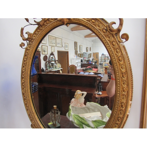 5472 - A 19th Century gilt gesso oval wall mirror, scrolled detail, shell relief, some losses, 89cm x 56cm ... 