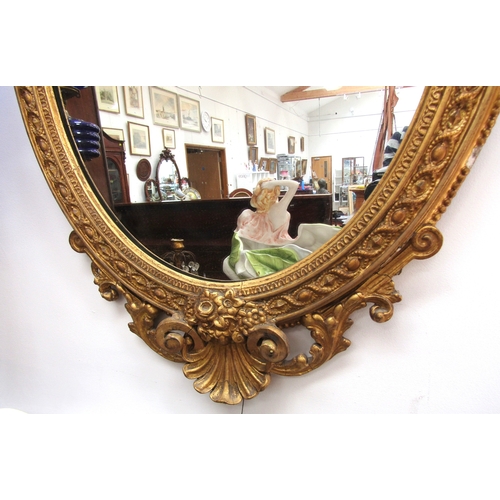 5472 - A 19th Century gilt gesso oval wall mirror, scrolled detail, shell relief, some losses, 89cm x 56cm ... 