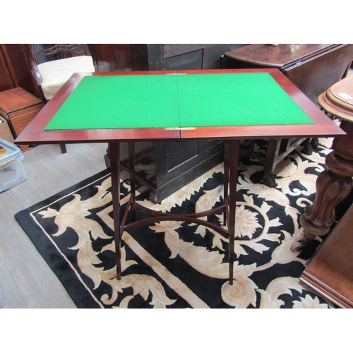 5507 - An Edwardian crossbanded mahogany games table, the fold over baize swivel top on a shape frieze and ... 