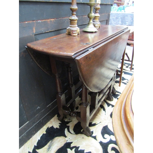 5508 - An 18th Century (Queen Anne Period) pegged oak oval top gate-leg table, the rising leaves over a sin... 