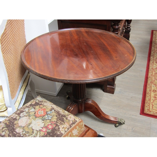 5521 - A 19th Century mahogany wine table, the dished top over a fluted column to a tripod base with brass ... 