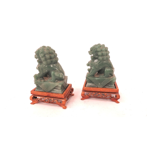 5046 - A pair of Chinese carved jade figures of dogs of fo on carved footed stands, 12.5cm tall