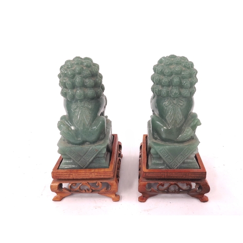 5046 - A pair of Chinese carved jade figures of dogs of fo on carved footed stands, 12.5cm tall