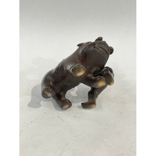 5058 - A bronze figural incense burner as a man holding the tail of a boar, 12.5cm high