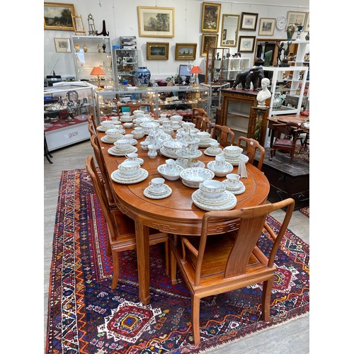 5696A - A teak Burmese oval extending dining table with 3 extra leaves and 10 chairs,  270cm long