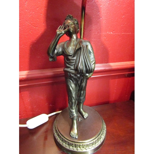 4133 - A brass and spelter table lamp of figural form, newspaper boy, with a green pleated shade, 62cm tall