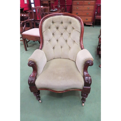 4165 - A Victorian button back armchair with scroll arms on turned fore legs to ceramic castors