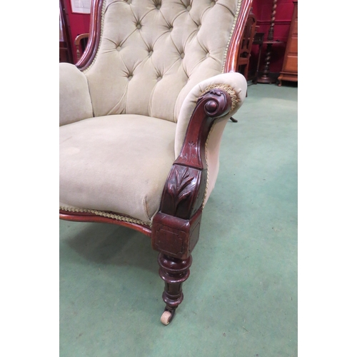 4165 - A Victorian button back armchair with scroll arms on turned fore legs to ceramic castors
