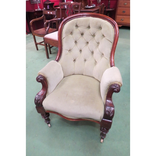 4165 - A Victorian button back armchair with scroll arms on turned fore legs to ceramic castors