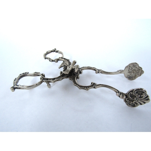 4312 - A pair of unmarked 18th Century sugar nips, the pivot surmounted by dove, the ends engraved and a pa... 