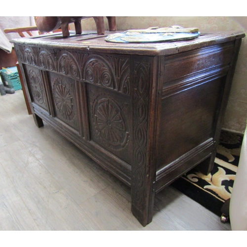 1084 - A 17th Century oak coffer, the four panel top over a heavily carved three panel front, spiral and fo... 