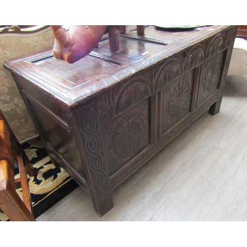 1084 - A 17th Century oak coffer, the four panel top over a heavily carved three panel front, spiral and fo... 