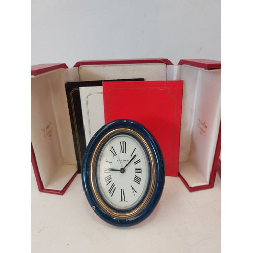 1332 - A Cartier travelling alarm clock, boxed, and a matching small oval photograph frame, boxed (2)