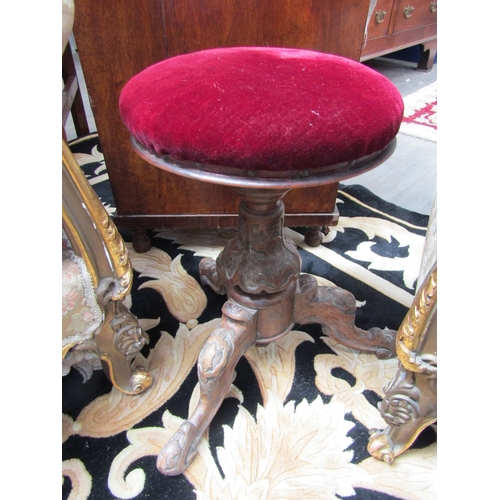 1096 - A Victorian carved music stool on tripod feet, red velour seat