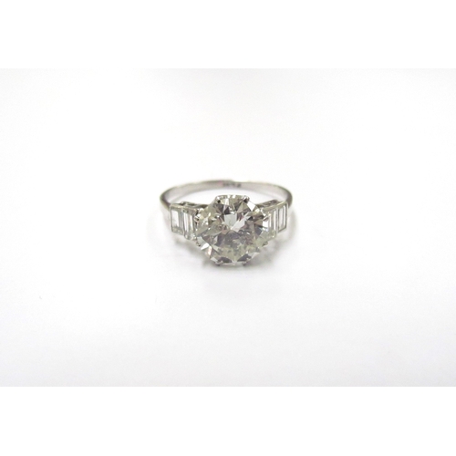 9300 - A platinum diamond solitaire 2.35ct approx flanked by two baguette diamonds. Size O, 3.3g