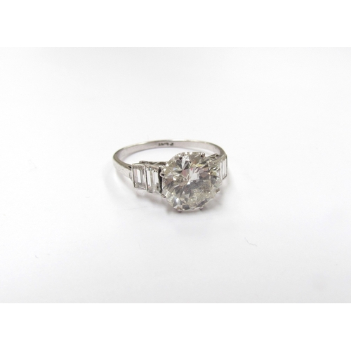 9300 - A platinum diamond solitaire 2.35ct approx flanked by two baguette diamonds. Size O, 3.3g