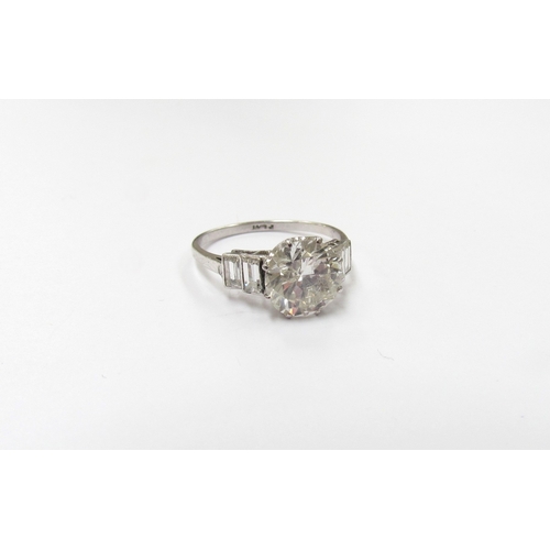 9300 - A platinum diamond solitaire 2.35ct approx flanked by two baguette diamonds. Size O, 3.3g