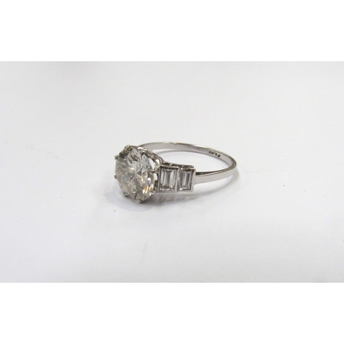 9300 - A platinum diamond solitaire 2.35ct approx flanked by two baguette diamonds. Size O, 3.3g