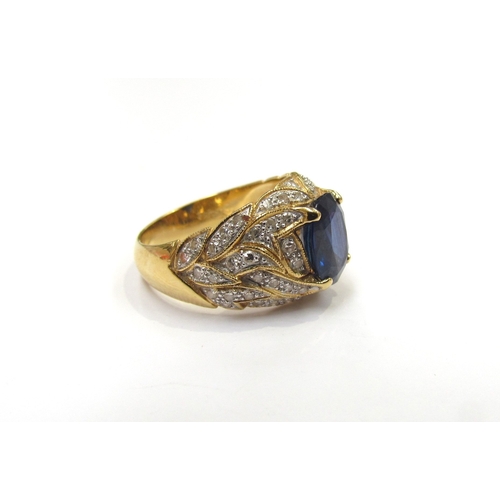 9279 - A yellow gold ring set with a single oval sapphire with flame style milgrain edge patterned mount se... 