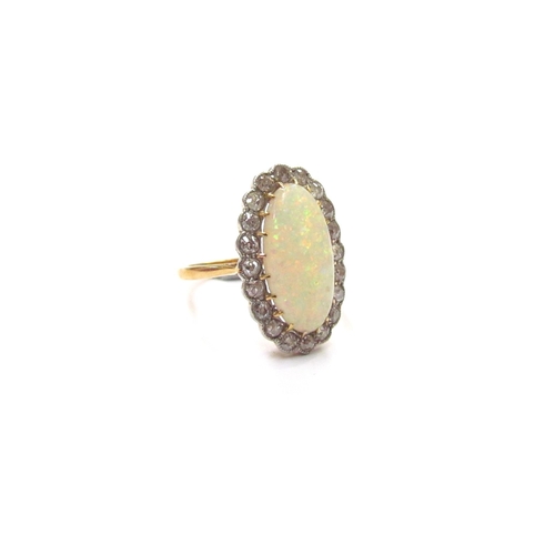 9288 - An 18ct gold platinum set opal and diamond ring, the central oval opal 15mm x 8mm framed by diamonds... 