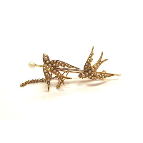 9155 - An unmarked gold brooch as two seed pearl set swallows, with safety chain, 5.5cm long, 6.3g