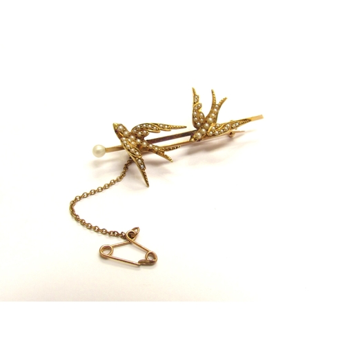 9155 - An unmarked gold brooch as two seed pearl set swallows, with safety chain, 5.5cm long, 6.3g