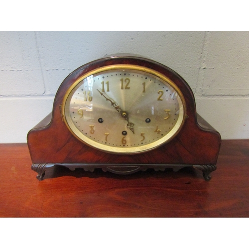 1071 - An early 20th Century oak oval mantel clock with brass plaque to reverse, with key