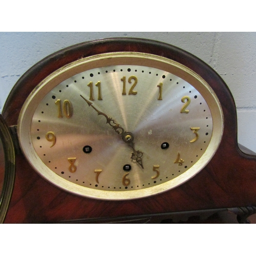 1071 - An early 20th Century oak oval mantel clock with brass plaque to reverse, with key