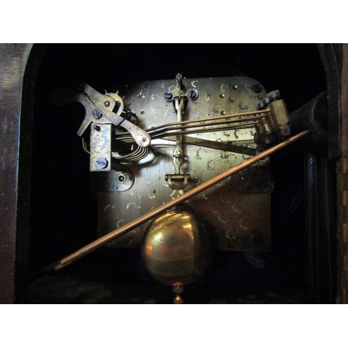 1071 - An early 20th Century oak oval mantel clock with brass plaque to reverse, with key